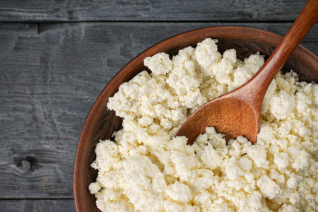 Rustic Bowl of Fresh Cottage Cheese on Wooden Table with Wooden Spoonの写真素材