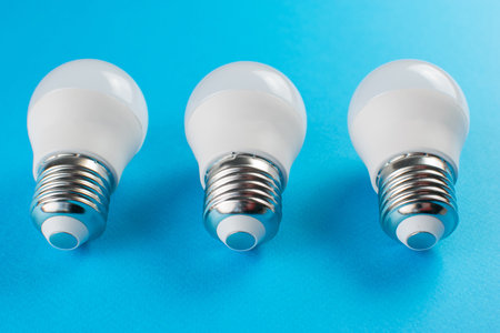 Three LED Light Bulbs on Vibrant Blue Background Highlight Energy-Efficient Lightingの写真素材