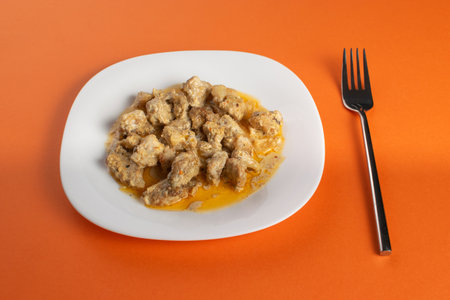 Delicious Homemade Gnocchi in Creamy Sauce on White Plate with Fork on Orange Backgroundの写真素材