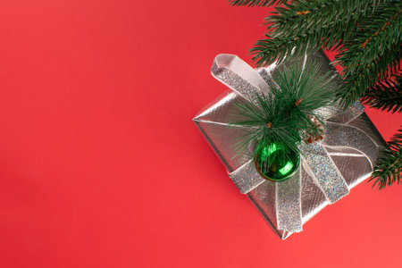 Festive Silver Gift Box with Green Ornament on Red Background for Christmas Celebrationの写真素材