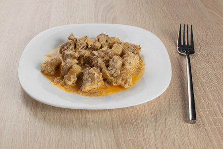 Savory Meat Stew on White Plate with Fork on Wooden Tableの写真素材