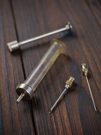 Vintage Medical Syringe with Metal Needles on Rustic Wooden Surfaceの写真素材