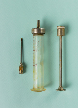 Vintage Medical Equipment on Blue Background: Antique Syringe with Needle and Plunger Displayの写真素材