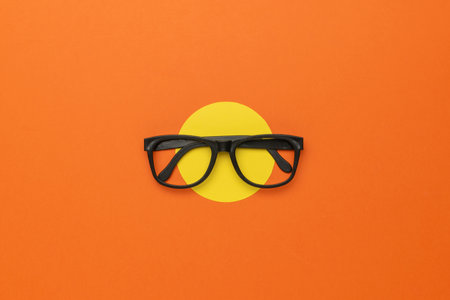 Black Glasses on Orange and Yellow Minimalist Background - Modern Eyewear Concept Photographyの写真素材