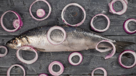 Fresh Herring with Red Onion Rings on Rustic Wooden Surface for Culinary Inspirationの写真素材