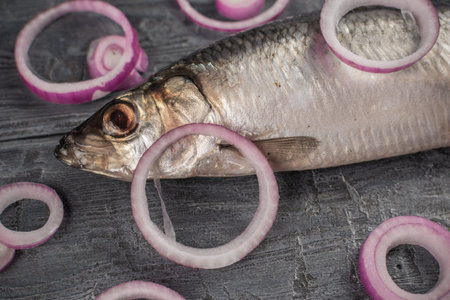 Fresh Herring with Red Onion Rings on Rustic Wooden Table - A Perfect Combination of Flavor and Textureの写真素材