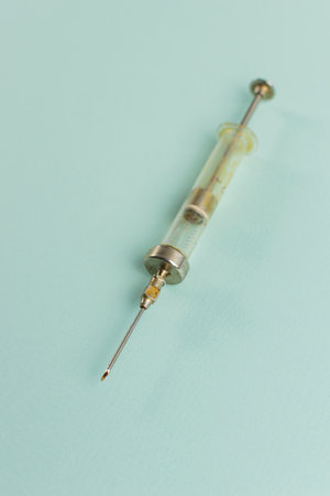 Vintage Medical Syringe on Blue Background: Retro Healthcare Equipment and Medical Toolsの写真素材