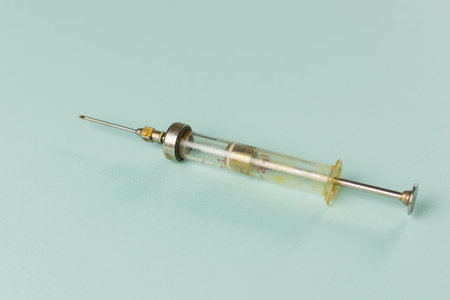 Vintage Glass Syringe on Pastel Background: Nostalgic Medical Instrumentの写真素材