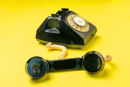 Vintage Rotary Phone with Off-The-Hook Receiver on Bold Yellow Backgroundの写真素材