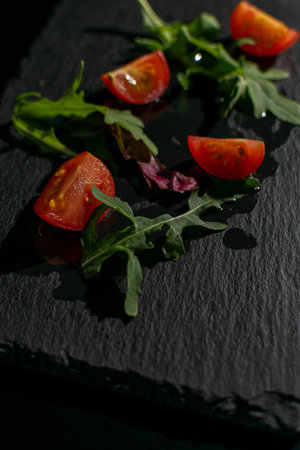Fresh Arugula and Cherry Tomatoes on Slate - Dark Food Photography Conceptの写真素材