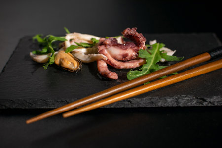 Gourmet Seafood Platter with Octopus, Mussel, and Arugula on Slate with Chopsticksの写真素材