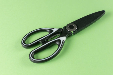 Black Kitchen Scissors on Vibrant Green Background for Modern Culinary Settingsの写真素材