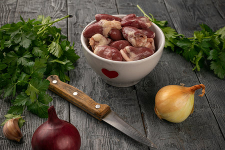 Fresh Chicken Hearts with Onions and Parsley on Rustic Wooden Tableの写真素材