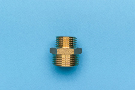 Brass Pipe Fitting on Blue Background: Plumbing and Construction Component Highlightの写真素材