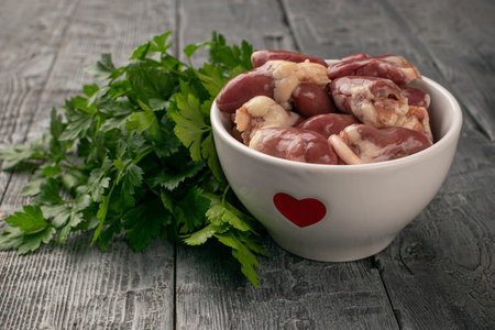 Fresh Chicken Hearts in Bowl with Parsley on Rustic Wood Table - Culinary and Food Conceptsの写真素材