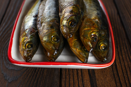 Grilled Sardines in Red-Trimmed Tray on Rustic Wooden Tabletopの写真素材