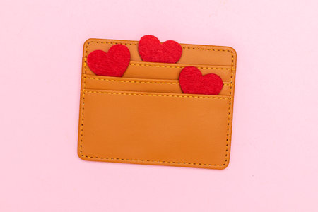 Brown Wallet with Red Heart Felt Accents on Pink Background: Love and Finances Conceptの写真素材