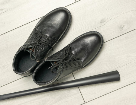 **Sleek Black Leather Shoes on Light Wood Floor with Matching Walking Stickの写真素材