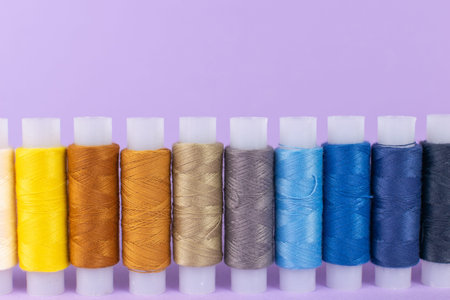 Colorful Spools of Thread on Purple Background Showcasing Rainbow Spectrum for Sewing and Crafting...