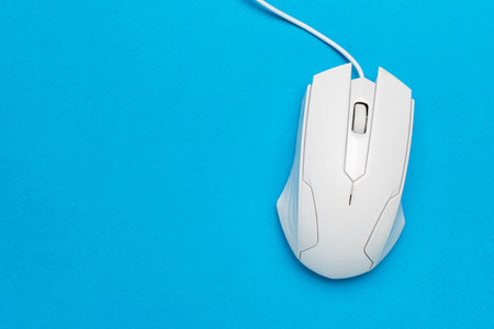White Wired Computer Mouse on Vibrant Blue Background: Minimalist Tech Design