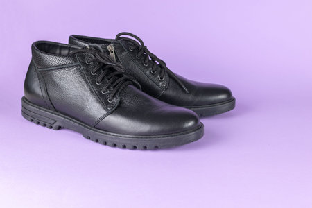 Stylish Black Leather Ankle Boots on Purple Background for Fashion and Footwear Trends