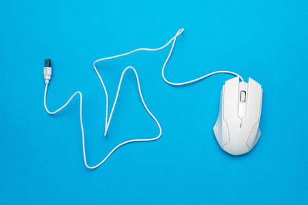 White Wired Computer Mouse on Blue Background with Curled Cable Designの写真素材