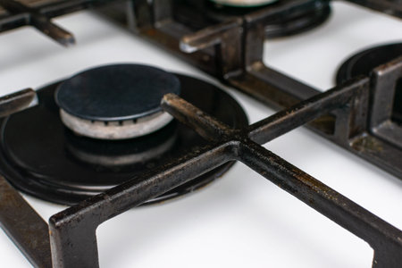 Close-Up of Black Metal Gas Stove Burners on a White Kitchen Cooker