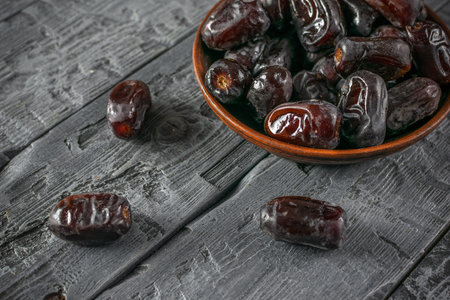 Close-Up of Dark Brown Dates in a Wooden Bowl on a Rustic Wooden Table