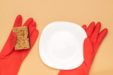 Brightly Colored Cleaning Concept with Red Gloves, Sponge, and White Plate on Minimalist Background