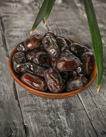 Rustic Bowl of Fresh Dates on Weathered Wooden Table with Green Leaf Accents