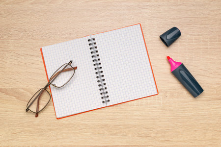 Open Notebook with Glasses and Highlighter on Wooden Desk