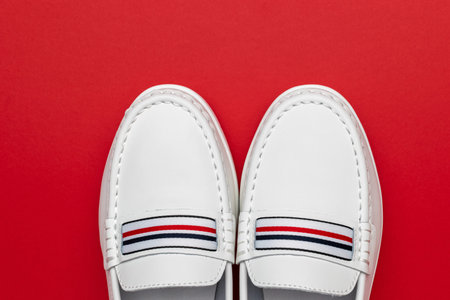 Stylish White Loafers on Bold Red Background with Striped Detail