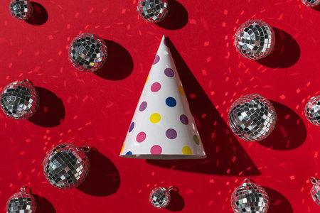 Festive Party Hat and Disco Balls on Vibrant Red Background - Celebratory Stock Photo