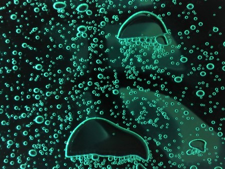 Close - up of air bubbles of different colors, in water isolated on dark background.