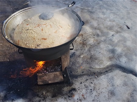 Fresh pilaf in a large cauldron cauldron is cooked on fire, outdoors in winter