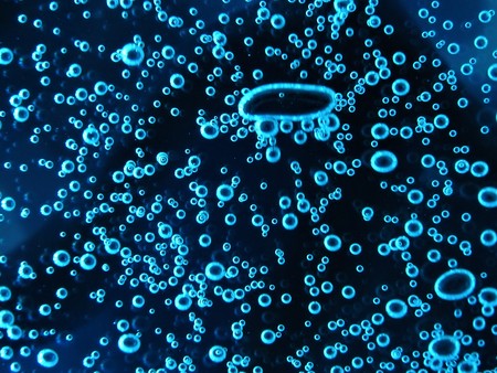 Close - up of air bubbles of different colors, in water isolated on dark background.