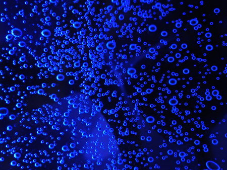 Close - up of air bubbles of different colors, in water isolated on dark background.