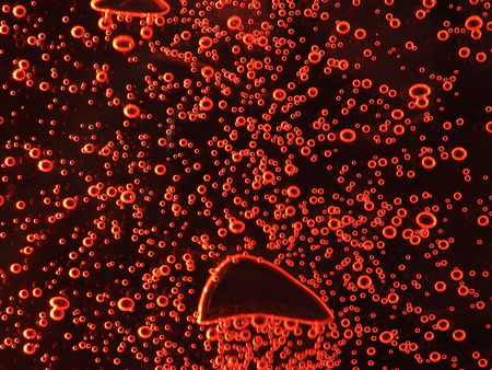 Close - up of air bubbles of different colors, in water isolated on dark background.