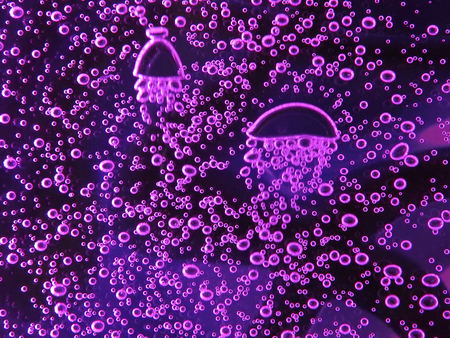 Close - up of air bubbles of different colors, in water isolated on dark background.