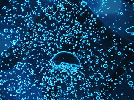 Close - up of air bubbles of different colors, in water isolated on dark background.
