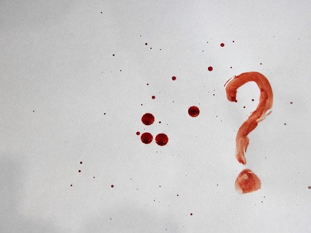 Spots and drops of fresh blood on a white background and a question markの写真素材