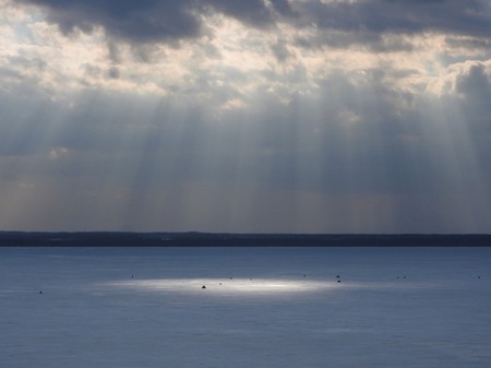 Ice frozen lake on a Sunny winter day in Russia. White snow and clouds in the blue sky. Beautiful...