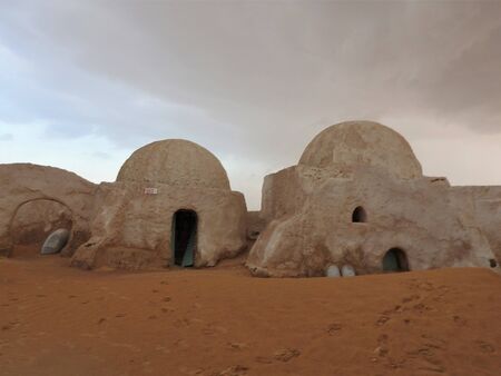 Sahara, Tunisia, July 25, 2018: abandoned scenery for the filming of "Star wars" in the Sahara desert, the planet Tatooine on the background of sand dunes. Defocusing against the background of a rare sandstorm in the desertのeditorial素材