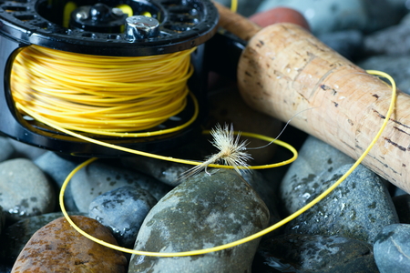 Fly fishing rod and bait lie on the rocks.