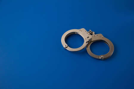Closed handcuffs on blue backgroundの写真素材