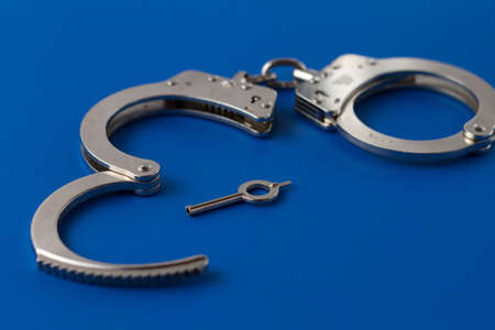 Open handcuffs with key on blueの写真素材