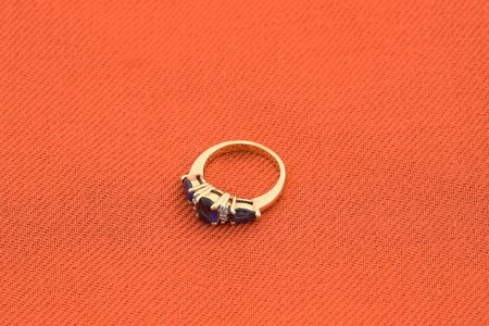 jewelery 022 gold ring with blue stone red background.の写真素材