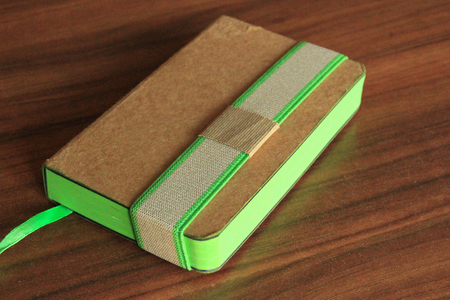 Photo of brown and green note book on table.の写真素材