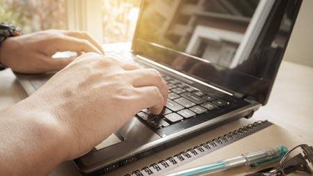 Young man working with laptop, man's hands on notebook computerの写真素材
