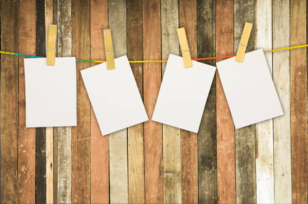 empty white photo frames hanging with clothespins on wooden backgroundの写真素材